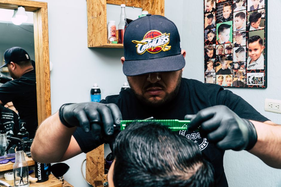Barber wearing gloves skillfully cutting a man's hair in a modern barbershop.